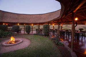 eine Terrasse mit einer Feuerstelle mit Tischen und Stühlen in der Unterkunft Lalibela Game Reserve Lentaba Safari Lodge in Paterson