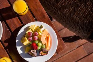 une assiette de fruits sur une table avec un verre de jus d'orange dans l'établissement Lalibela Game Reserve Lentaba Safari Lodge, à Paterson