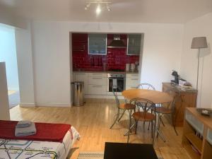 een keuken met een tafel en stoelen in een kamer bij Cozy 1 Bedroom Basement Flat in Londen