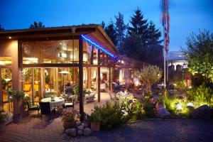 un edificio con un patio con mesas, sillas y plantas en EUT-IN Hotel Alte Straßenmeisterei, en Eutin