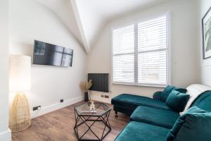 a living room with a green couch and a tv at Watergate Penthouse - NEW 2 bed luxury apartment in City Centre in Chester