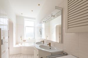 a white bathroom with a sink and a mirror at Haus Decker, App 2 in Wenningstedt +11 photos