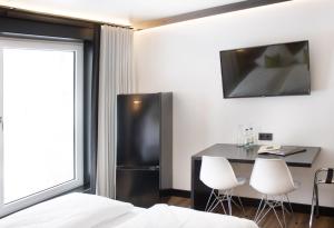 een kamer met een koelkast en een tafel en stoelen bij BLB Hotel by WMM Hotels in Blaubeuren