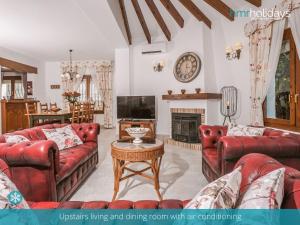 een woonkamer met rode banken en een open haard bij Villa Talia by HMR Holidays Moraira in Moraira