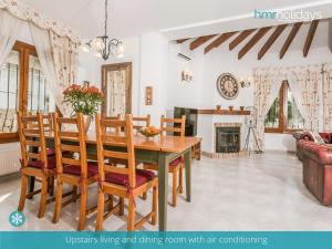 een eetkamer met een tafel en stoelen en een open haard bij Villa Talia by HMR Holidays Moraira in Moraira