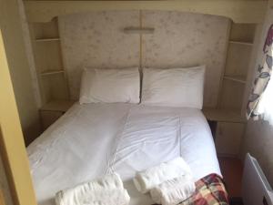 uma cama com lençóis brancos e almofadas num quarto em Skye Holiday Chalets C1 em Uig