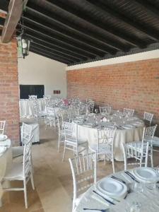 un salón de banquetes con mesas blancas y sillas blancas en PENSIUNEA ALEXANDRA en Zăbrani