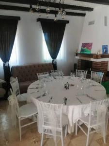 a table with white chairs and a white table with wine glasses at PENSIUNEA ALEXANDRA in Zăbrani