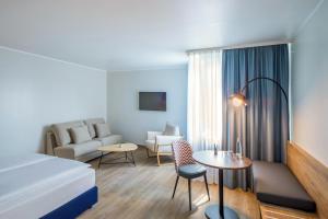 オーバーハウゼンにあるHotel Oberhausen Neue Mitte affiliated by Meliáのベッドとソファのあるホテルの部屋