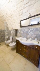 bagno con lavandino, servizi igienici e specchio di Martina Trulli Relais a Locorotondo