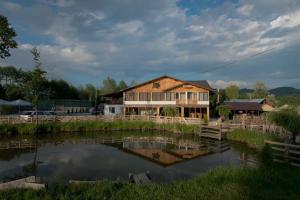 a house with a pond in front of it at La Helesteu in Lăzăreşti