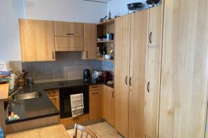cocina con armarios de madera y encimera negra en Bel appartement 2.5 pièces avec balcon, magnifique vue sur le glacier des Grands en Finhaut