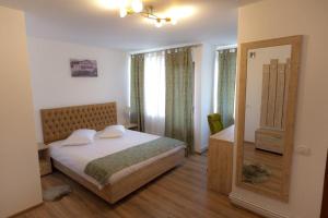 a bedroom with a bed and a mirror at La Helesteu in Lăzăreşti