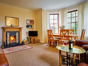 a living room with a fireplace and a table at West Lodge in Bridgend of Lintrathen