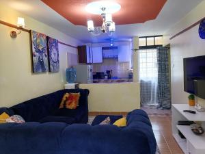 a living room with a blue couch and a kitchen at Lovely One bedroom Apartment , TRM Drive Nairobi in Nairobi