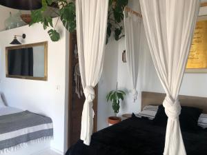 Schlafzimmer mit weißen Vorhängen, einem Bett und einem Spiegel in der Unterkunft Villa Dolina Hvar in Hvar
