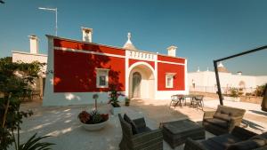 un patio con un edificio rojo y blanco con mesas y sillas en Martina Trulli Relais, en Locorotondo
