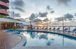 a swimming pool with chairs and the ocean in the background at Iate Plaza Beiramar Fortaleza app1006 in Fortaleza