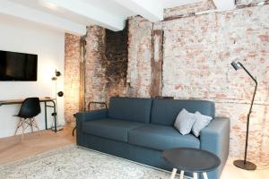 a living room with a blue couch and a brick wall at Hotel IX Nine Streets Amsterdam in Amsterdam