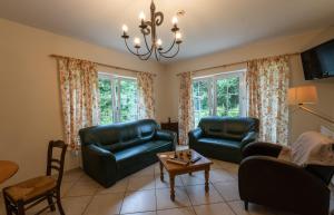 una sala de estar con muebles de cuero y una lámpara de araña. en Logement de Blauwe Reiger en Voeren
