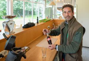 un hombre parado en un mostrador sosteniendo una copa de vino en Logement de Blauwe Reiger, en Voeren
