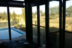 a room with windows looking out at a swimming pool at Cabaña Pirayú in Oliveros