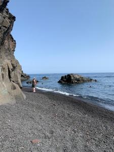 un niño parado en una playa rocosa cerca del océano en La Rosamarina en Stromboli