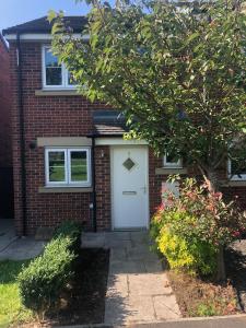 a brick house with a white door and a tree at Brockwell - 2 Bed Modern Home, Near City Centre in Bowburn