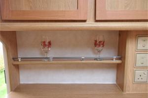two wine glasses sitting on a shelf in a kitchen at Y Ffau - A gorgeous little caravan in Knighton