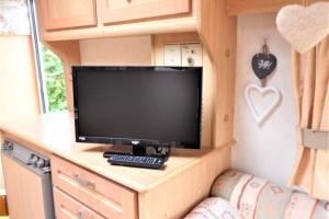 a tv on a desk in a tiny house at Y Ffau - A gorgeous little caravan in Knighton