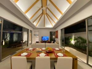 a dining room with a table and white chairs at Anchan Grand Residence Villa in Phuket Town