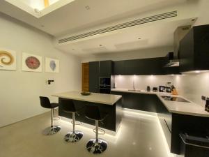 una cocina con encimeras y taburetes en blanco y negro en Anchan Grand Residence Villa en Phuket