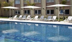 a group of chairs and umbrellas next to a swimming pool at Days Inn Zarate in Zárate