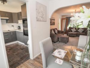 a kitchen and a living room with a table in a room at 28 Alwen Drive in Colwyn Bay
