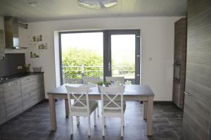 a kitchen with a wooden table and white chairs at Gîtes Paille-Foin in Cerfontaine