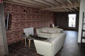 uma sala de estar com dois sofás e uma parede de tijolos em Gîtes Paille-Foin em Cerfontaine
