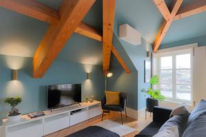 HM - Infante Riverside Apartment R في بورتو: غرفة معيشة مع جدران زرقاء وعوارض خشبية