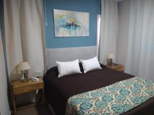 a bedroom with a bed and two tables with lamps at Village Condo in San Carlos de Bariloche