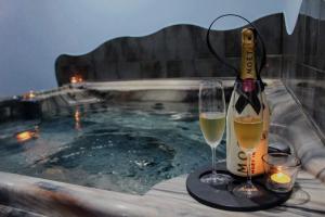 a bottle of champagne and two glasses next to a swimming pool at Wellness apartmán s vířivkou a saunou in Plzeň