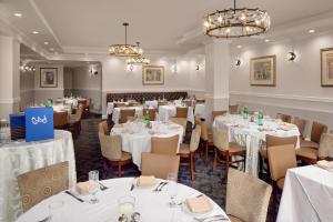 un comedor con mesas y sillas blancas en The Andrew Hotel, en Great Neck