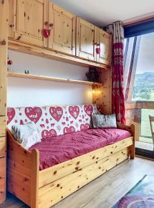 ein Schlafzimmer mit einem Holzbett und einem Fenster in der Unterkunft travelski home classic - Résidence Soyouz in Le Corbier