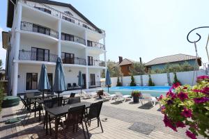 a hotel with tables and chairs next to a swimming pool at Villa Bonapart in Zatoka