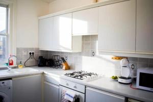 a kitchen with white cabinets and a stove top oven at GuestReady - Calm and Central sleeps up to 6 in Edinburgh