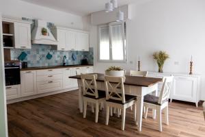 una cocina con armarios blancos y una mesa y sillas de madera. en LORA GIUSTA GUEST HOUSE, en Como