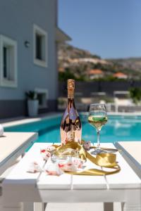 eine Flasche Wein und ein Glas auf einem Tisch am Pool in der Unterkunft Villa Ban in Trogir