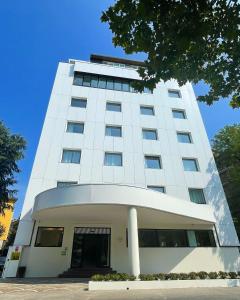 ein hohes weißes Gebäude mit einem Baum in der Unterkunft Hotel Morfeo in Mailand