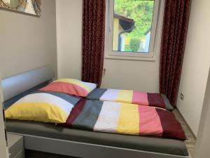 a bed with a colorful comforter and a window at Neurenovierte FeWo Harztor in Nordhausen