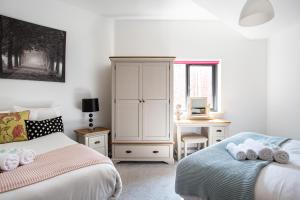 a bedroom with two beds and a dresser and a desk at Modern Luxury Apartment, Sleeps 6, Best Location in Belfast