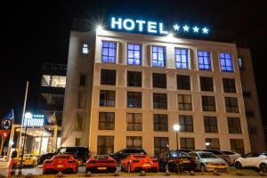 un hotel con coches aparcados delante de él por la noche en Hotel Avenue - Avenue Hotels, en Buzău