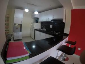 a kitchen with white cabinets and a black counter top at La casita de max y tim apt 201 in Cartagena de Indias